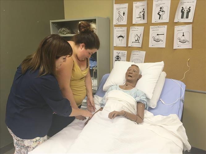 A student and instructor work with a patient simulator dummy