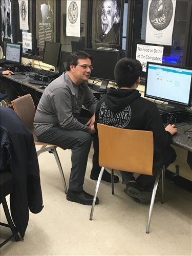 A teacher works with a student at a computer