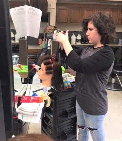 A student works on a hairstyle on a mannequin head