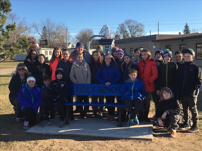 Students pose in front of the school yard's new Buddy Bench