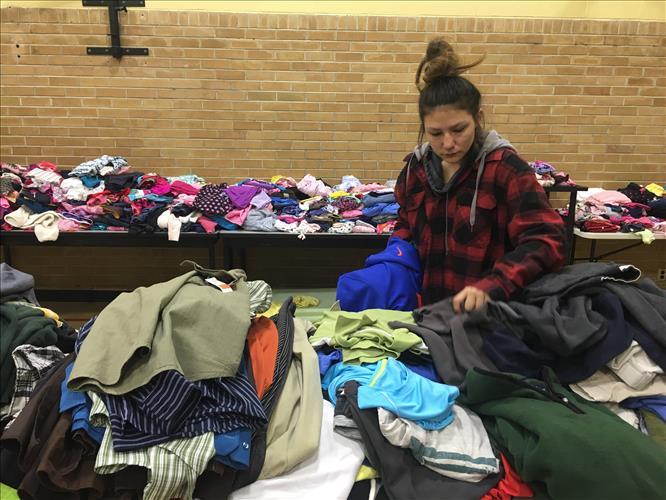 A young woman sorts through clothing donations