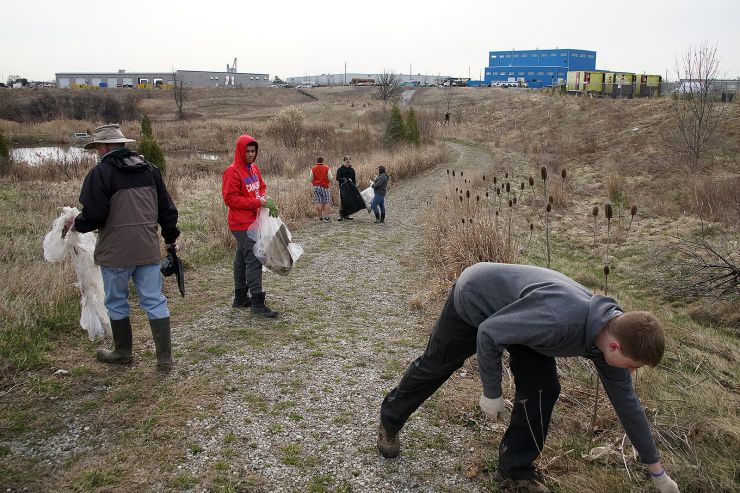 Students pick up trash in a grassy field