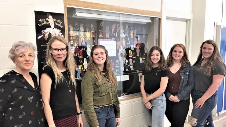 Librarian, Teacher, and students in the World Cultures class in front of the Faceless Dolls display