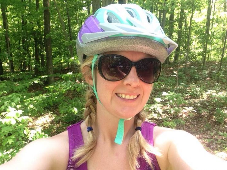 A woman wears a bike helmet and takes a selfie 