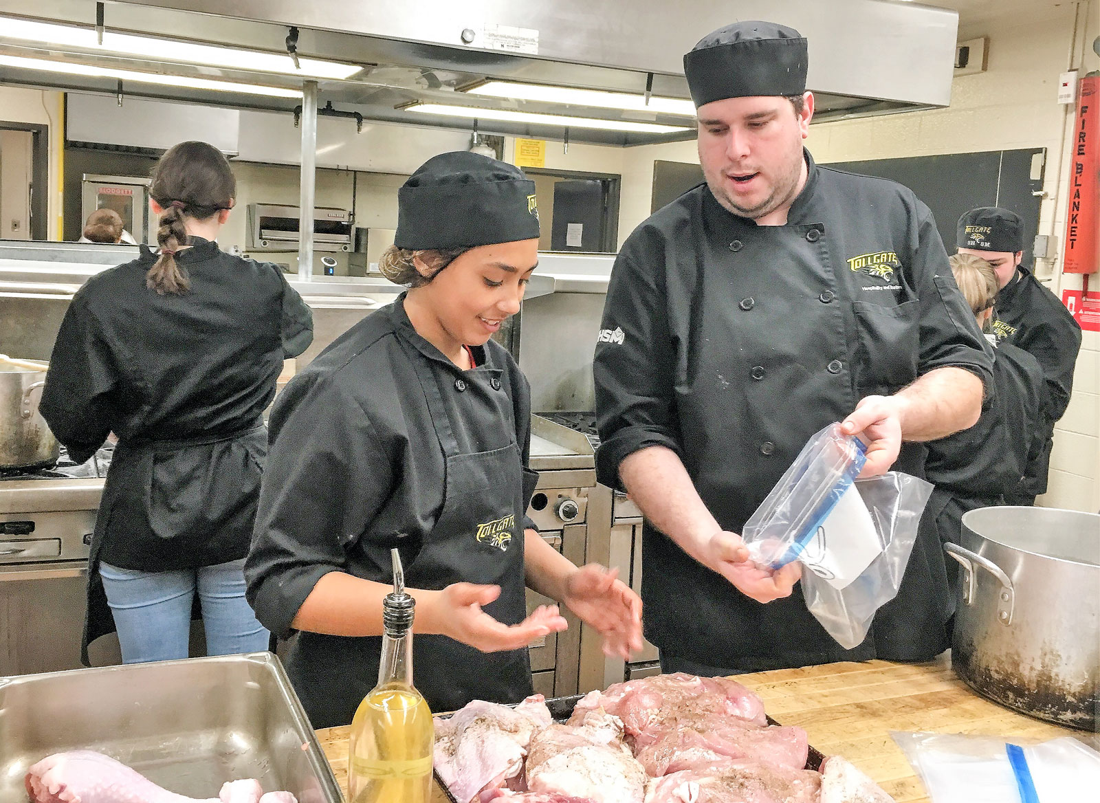 Food Technician Ryan Rockefeller works with student Serenity to prepare turkey.