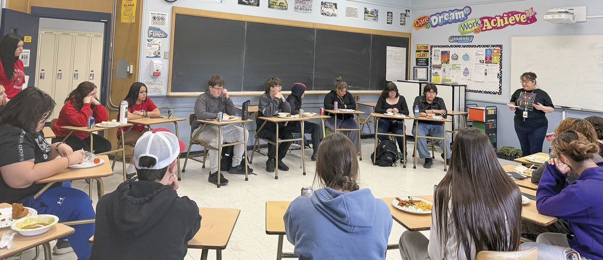 Students in classroom sitting at desks arranged in circle