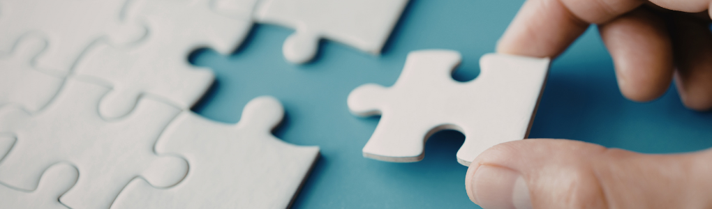 White puzzle with person putting last piece into place