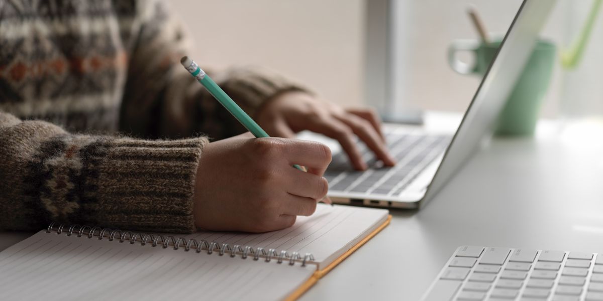 Close up of person e-learning writing in notebook