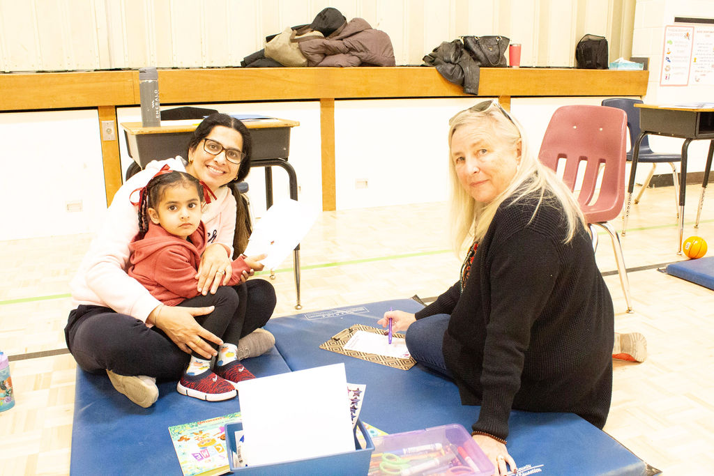 Mother and child sitting on the floor with staff