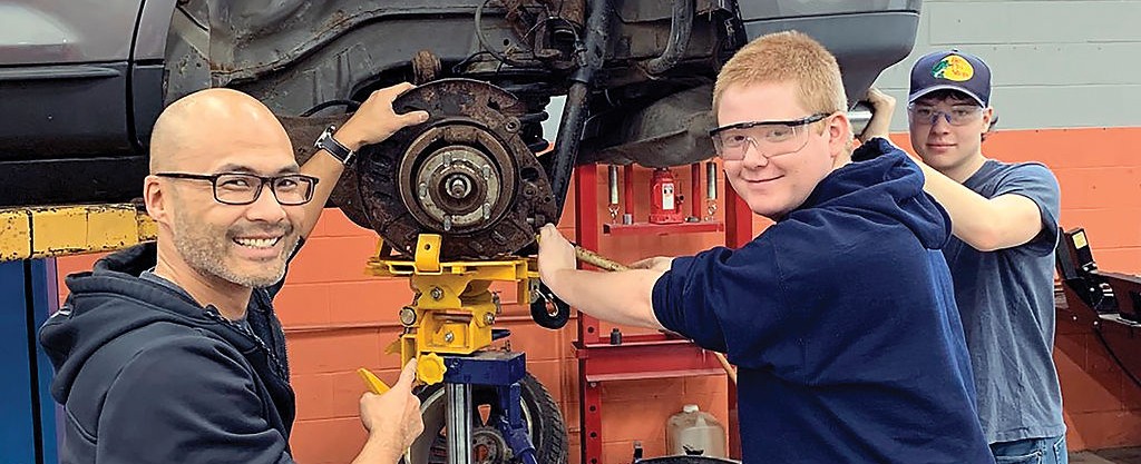 a teacher and student fixing a car