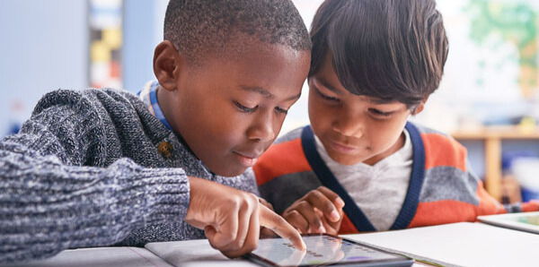 two kids reading from a tablet