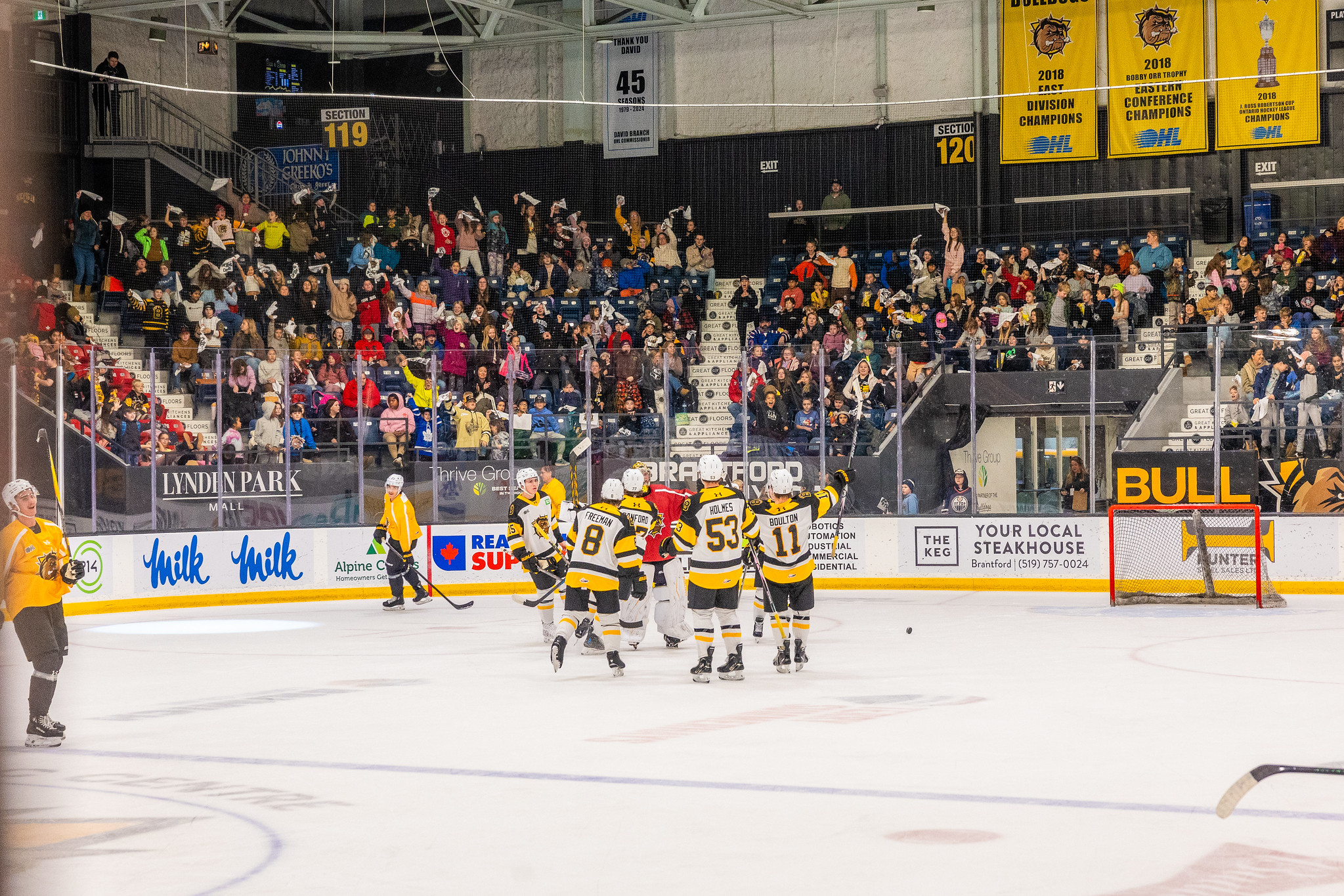 54948301648_35ccfa27f7_k A group of Brantford Bulldogs players gathering to celebrate during the skills competition with students in the background cheering.