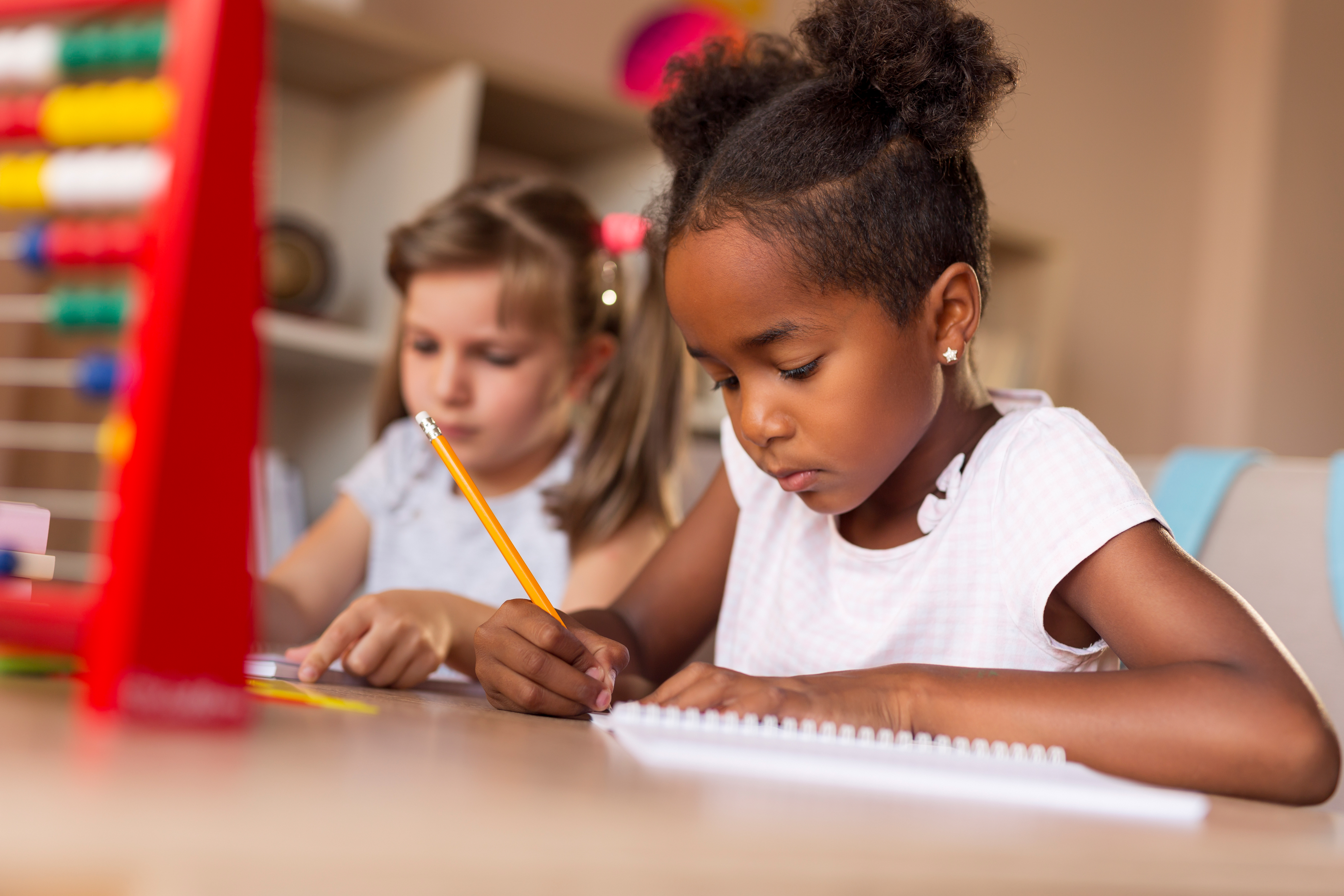Girls learning with pencils and notebooks in class