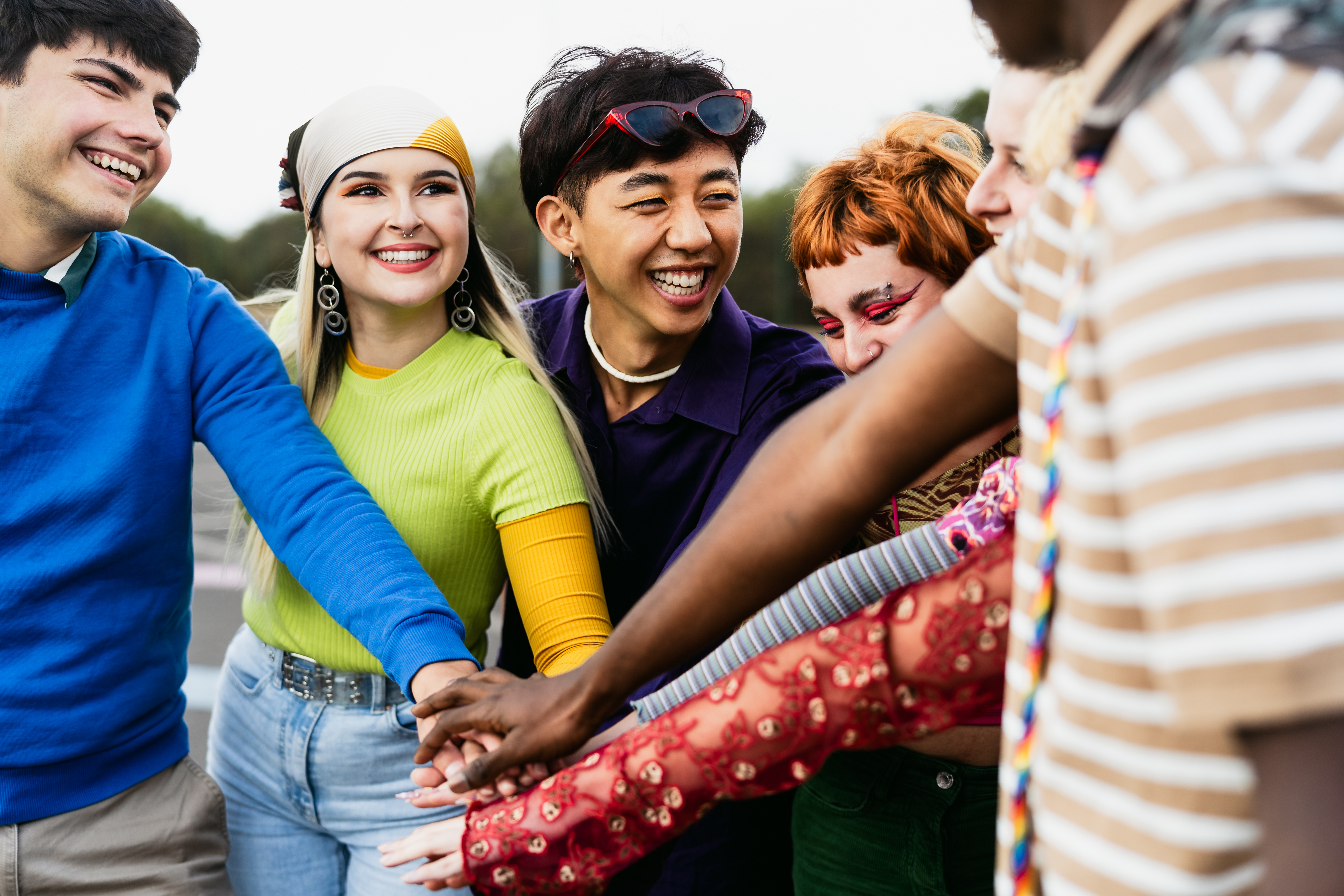 Happy young friends stacking hands