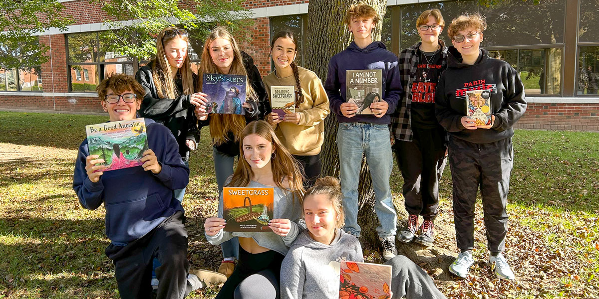 A group of Paris District High School students on school grounds displaying books promoting Truth and Reconciliation